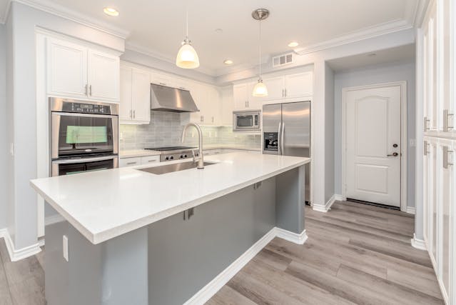 a kitchen with white counters and cabinets and a large island