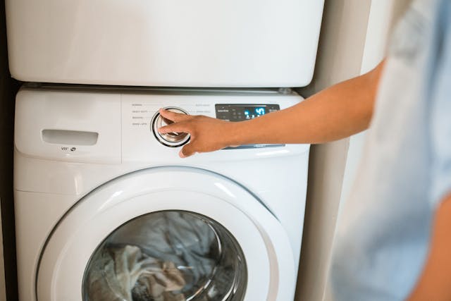 a person using a stacked washer and dryer