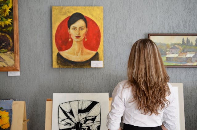 person looking at paintings displayed on a wall